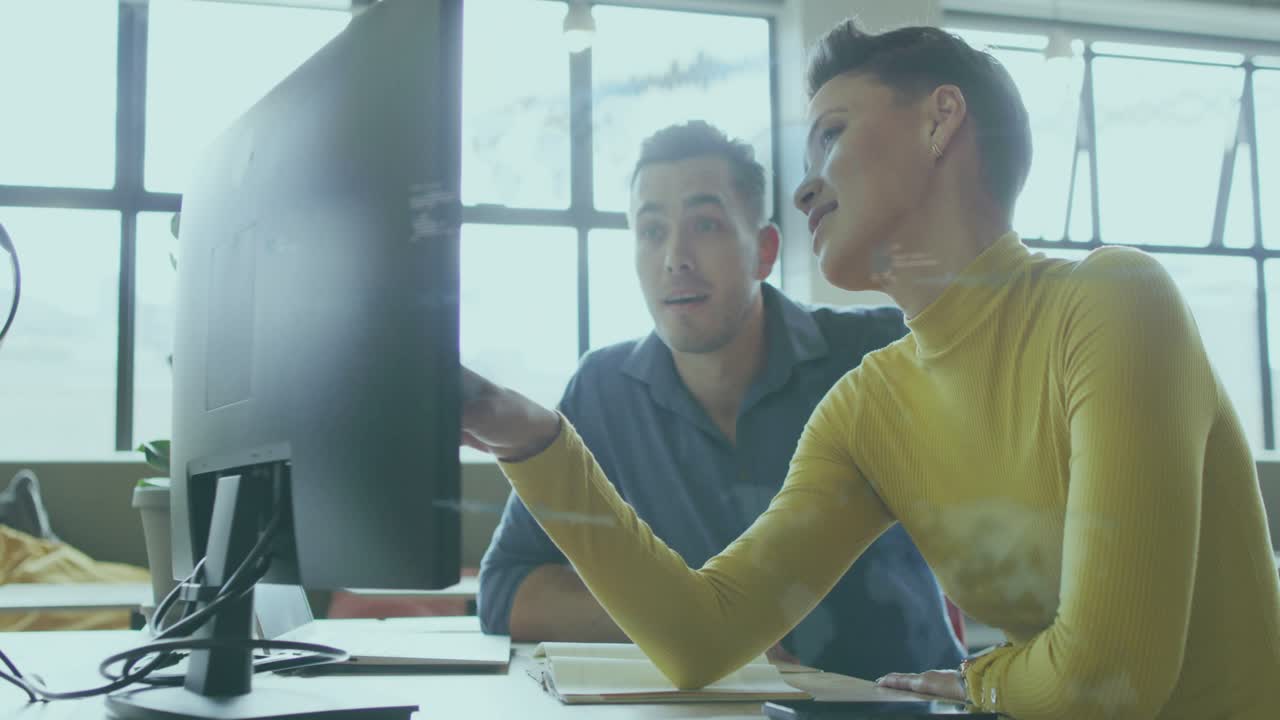 Woman pointing at monitor, guiding man, initiating tech overlays on faces, clarifying code
