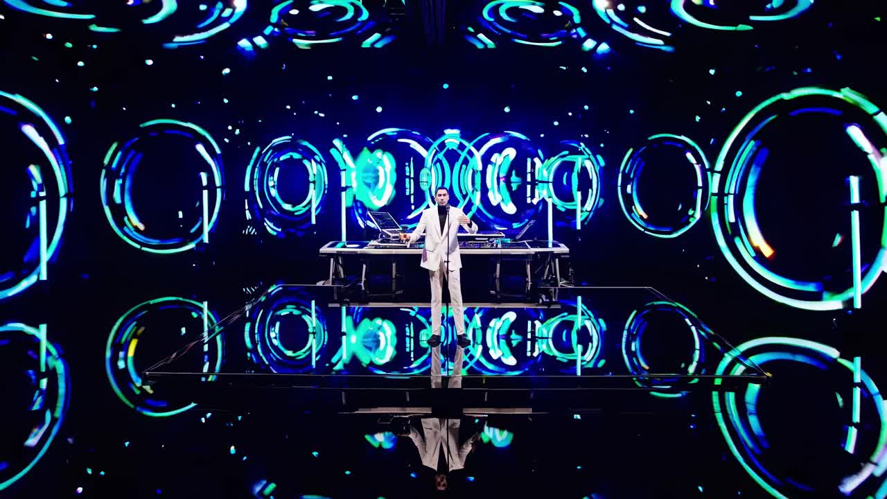 Futuristic concert stage features a musician playing electronic music surrounded by holographic circular visuals, creating an immersive and captivating atmosphere
