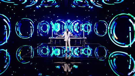 Futuristic concert stage features a musician playing electronic music surrounded by holographic circular visuals, creating an immersive and captivating atmosphere