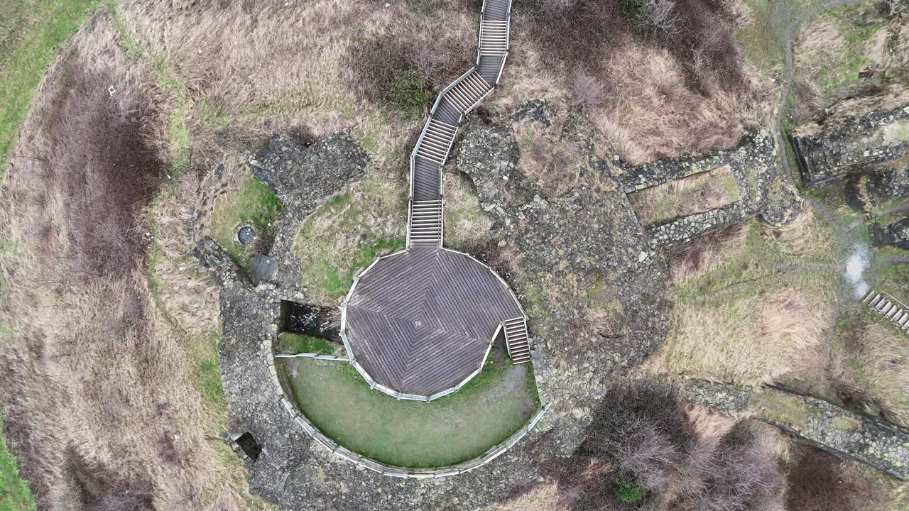Drone video captures the ancient, circular stone ruins of Dunnottar Castle in Scotland from above. The rugged terrain and weathered textures enhance its historic allure