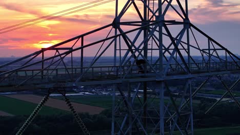 a base jumper prepares atop a tall metal tower at sunset with a city skyline in the distance