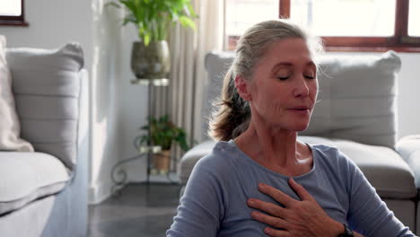 senior woman meditating at home, finding peace and relaxation in living room