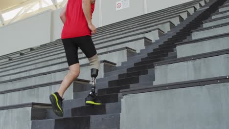 atleta masculino caucásico discapacitado con entrenamiento de piernas protésicas, subiendo escaleras corriendo