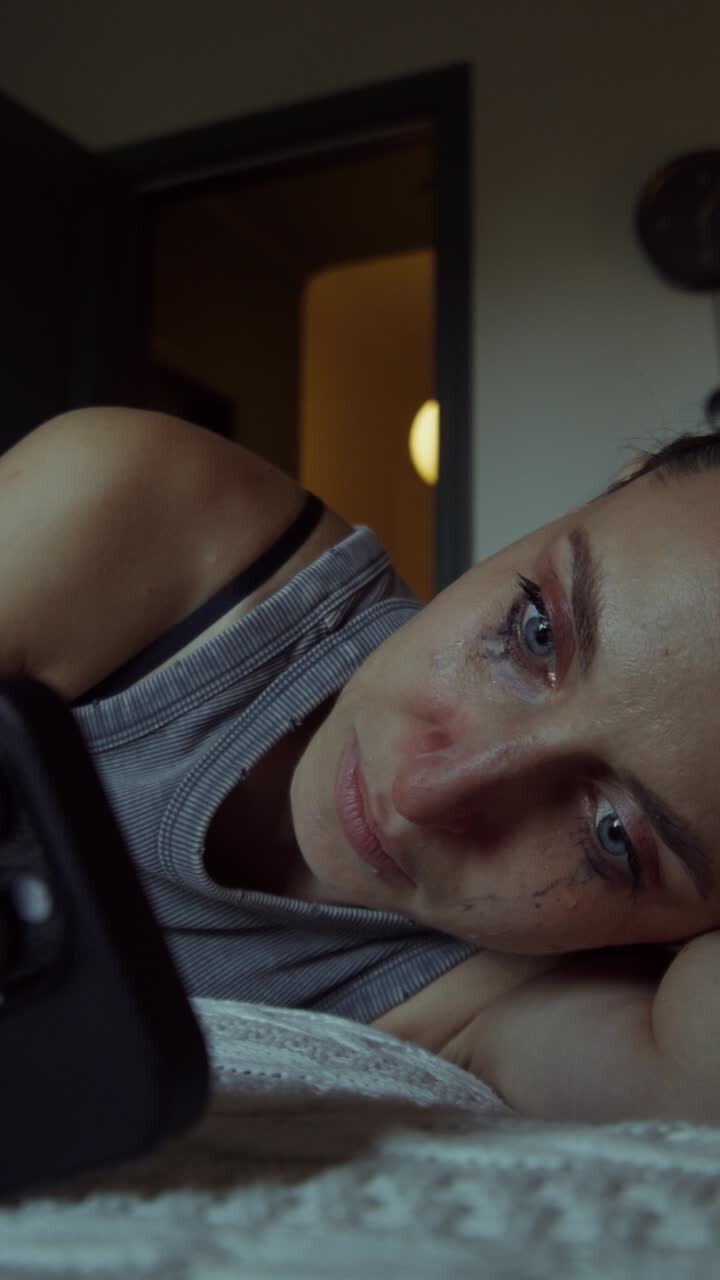 Sad Woman Lying in Bed Looking at Phone