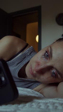 mujer triste acostada en la cama mirando el teléfono