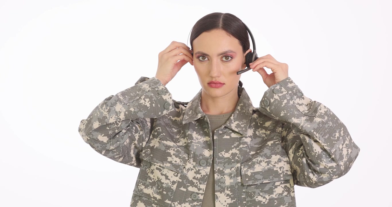 Vrouw in camouflage militair uniform stelt headset bij met haar handen