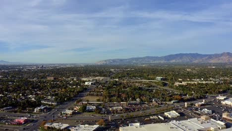 left trucking aerial drone extreme wide landscape shot of the salt lake county valley covered in buildings, busy roads, and colorful autumn trees on a warm sunny fall evening in utah