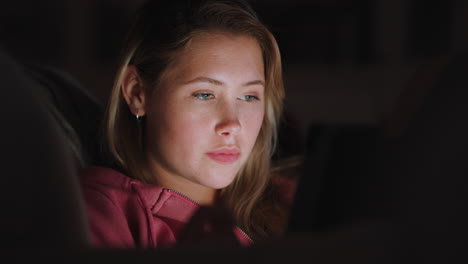 hermosa adolescente usando una tableta viendo entretenimiento por la noche navegando en línea disfrutando de una noche relajante