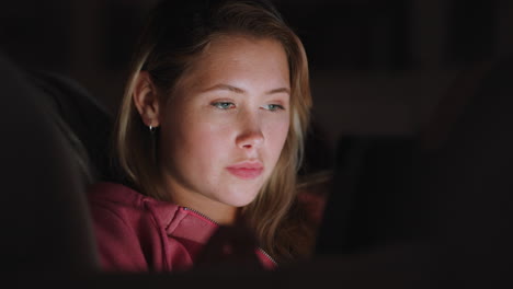 beautiful teenage girl using tablet computer watching entertainment at night browsing online enjoying relaxing evening