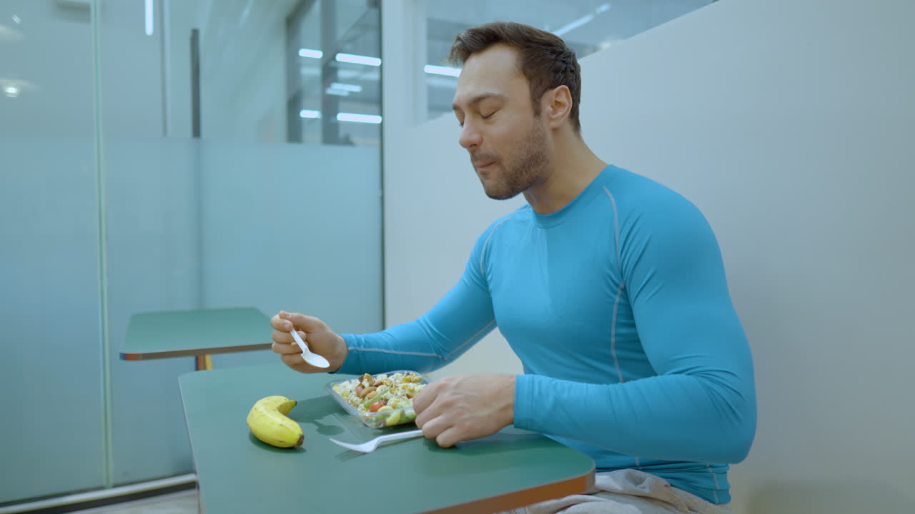 hombre deportivo comiendo ensalada saludable después del entrenamiento en el café del gimnasio - cámara lenta