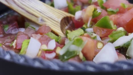 un primer plano vibrante de salsa fresca con tomates, cebollas, pimientos y cilantro mezclados