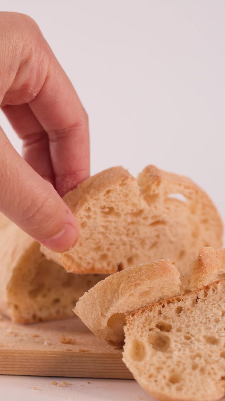 A hand reaches into frame to pick up a fresh sourdough slice from a board.