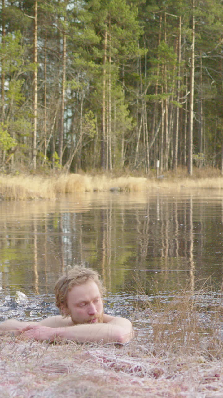 A fit, handsome ice bathing man enters a frozen lake for daily routine, vertical