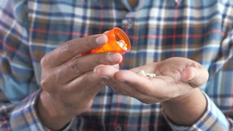 person taking pills from a bottle