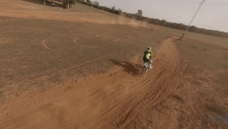 el veloz dron fpv alcanza al corredor de motos en una pista de tierra arenosa
