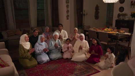multi-generational muslim family engaged in prayer at home during a celebration