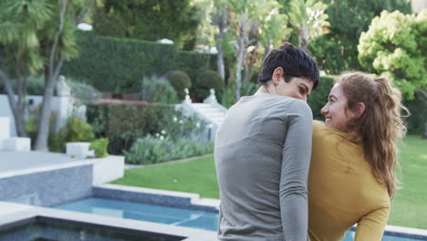 Happy-caucasian-lesbian-couple-standing,-embracing-and-smiling-in-front-of-house,-copy-space