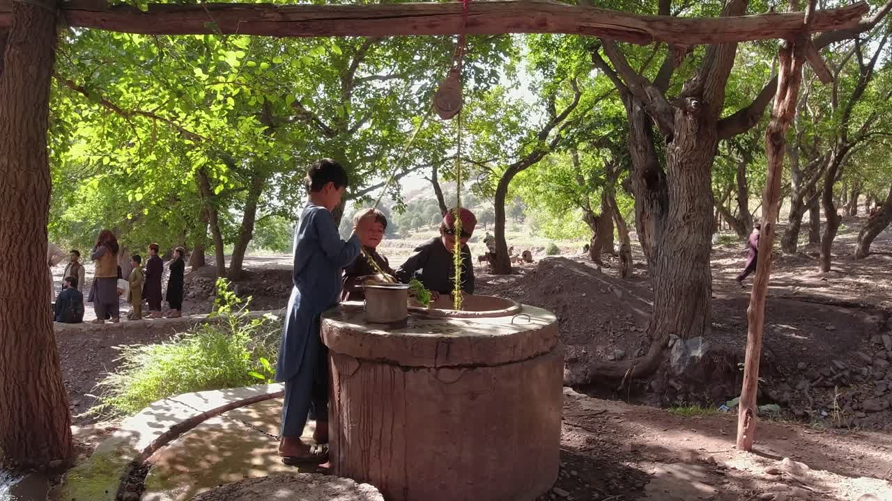 A child scooping water up with their hands from a well