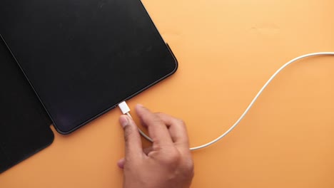 cargando el teléfono inteligente con un cable en el fondo de color