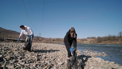 trabajo en equipo limpiando plástico en la playa. voluntarios recogen basura en una bolsa de basura. contaminación plástica y concepto de problema ambiental. limpieza voluntaria de la naturaleza del plástico. ecologización del planeta