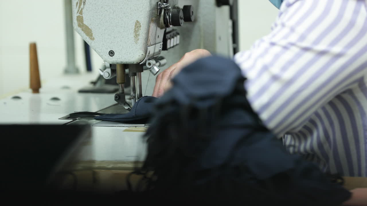 covid-19 발발 동안 많은 수의 파란 얼굴 마스크를 재봉하는 재봉 공장 재봉사 - 중간 샷 팬 왼쪽