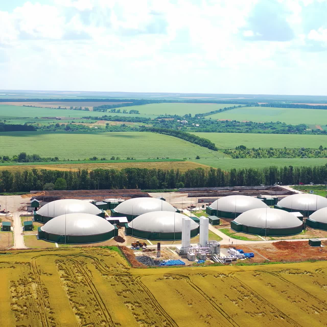 Biogas complex on green nature background. Renewable energy. Modern plant for production of biogas on field. Aerial view