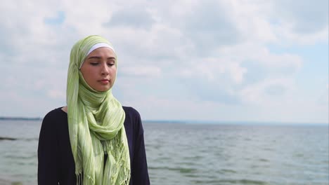 young woman in hijab by the lake