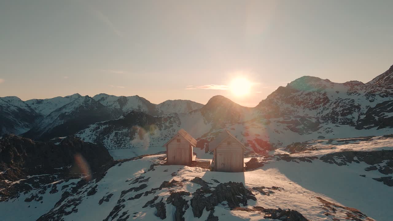 drone volando sobre dos cabañas al amanecer