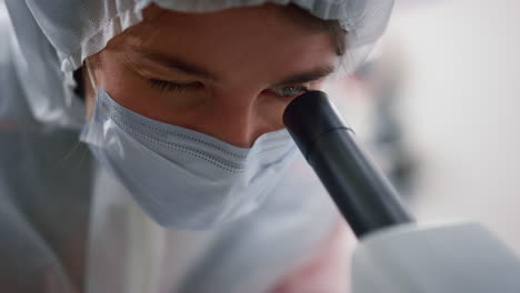 Female-scientist-looking-through-microscope-in-laboratory