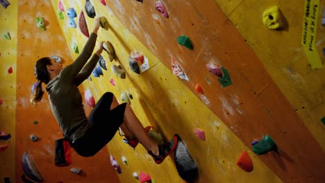 Frau-Klettert-An-Der-Künstlichen-Wand-In-Der-Boulderhalle-4k