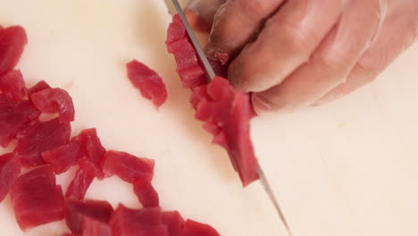 도마에 칼을 사용하여 참치 고기를 작은 조각으로 자르는 요리사