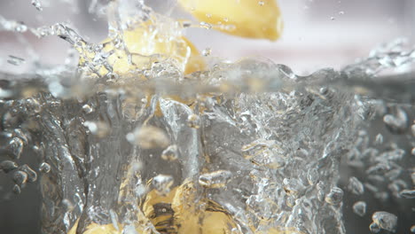 patatas descascaradas caídas en una olla de agua hirviendo sumergirse en el fondo de los utensilios de cocina, macro y cámara lenta