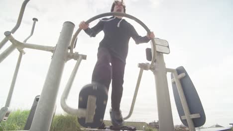 young man in black on leg swing equipment outdoors daytime working out