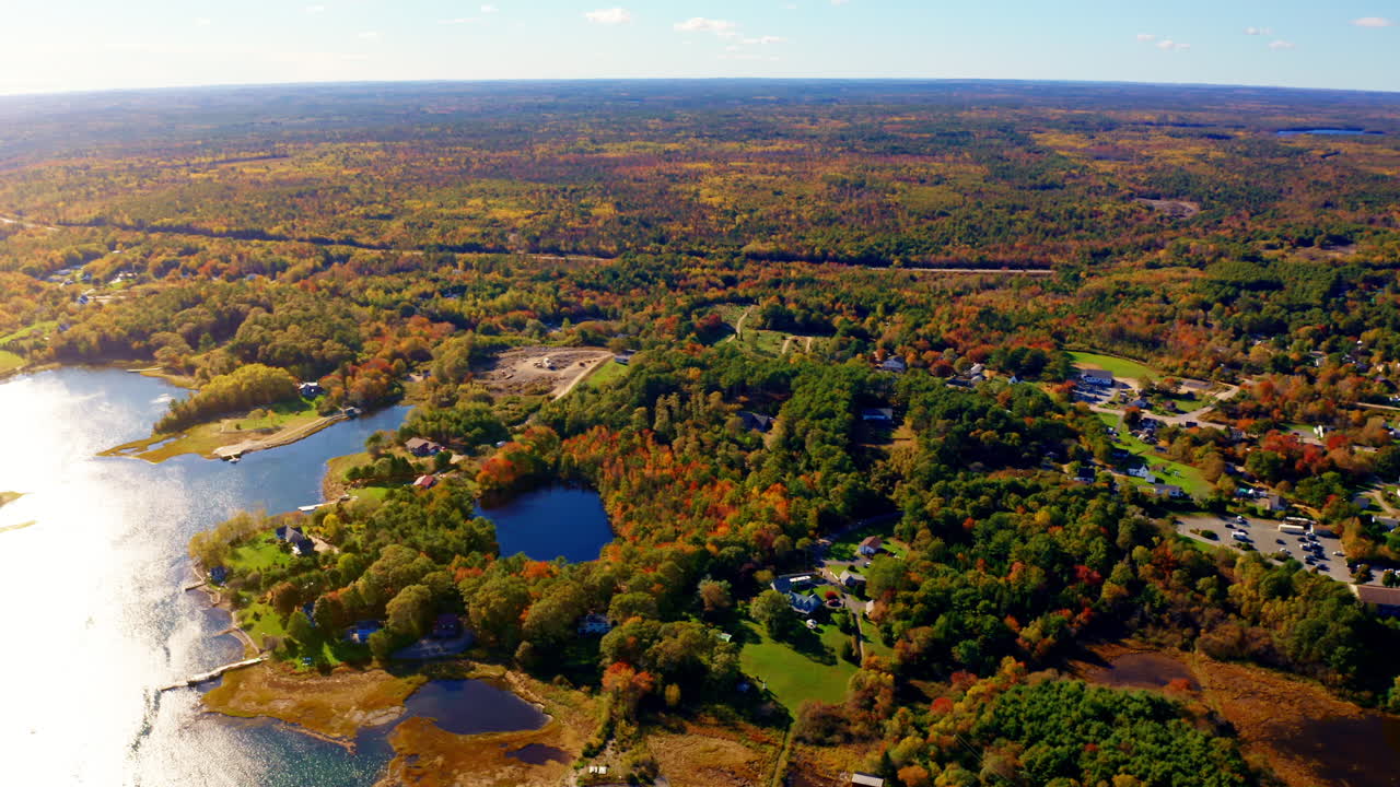 Aerial drone shot over the coastline of Oak Island, Nova Scotia, Canada.
High view of the sea, autumn colorful trees foliage. Picturesque landscape. Fall vibrant colors.