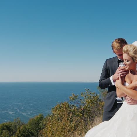 the bride and groom in a wedding dress standing on the background of the sea looking into the distance