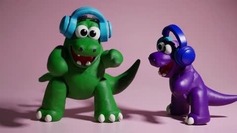 two cheerful plasticine dinosaurs wearing headphones are dancing joyfully, grooving to music together against a vibrant pink background, radiating fun and playful energy