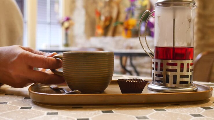 Mano che prende una tazza di tè caldo da un tavolino da caffè