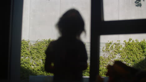 little girl combing hair against the window