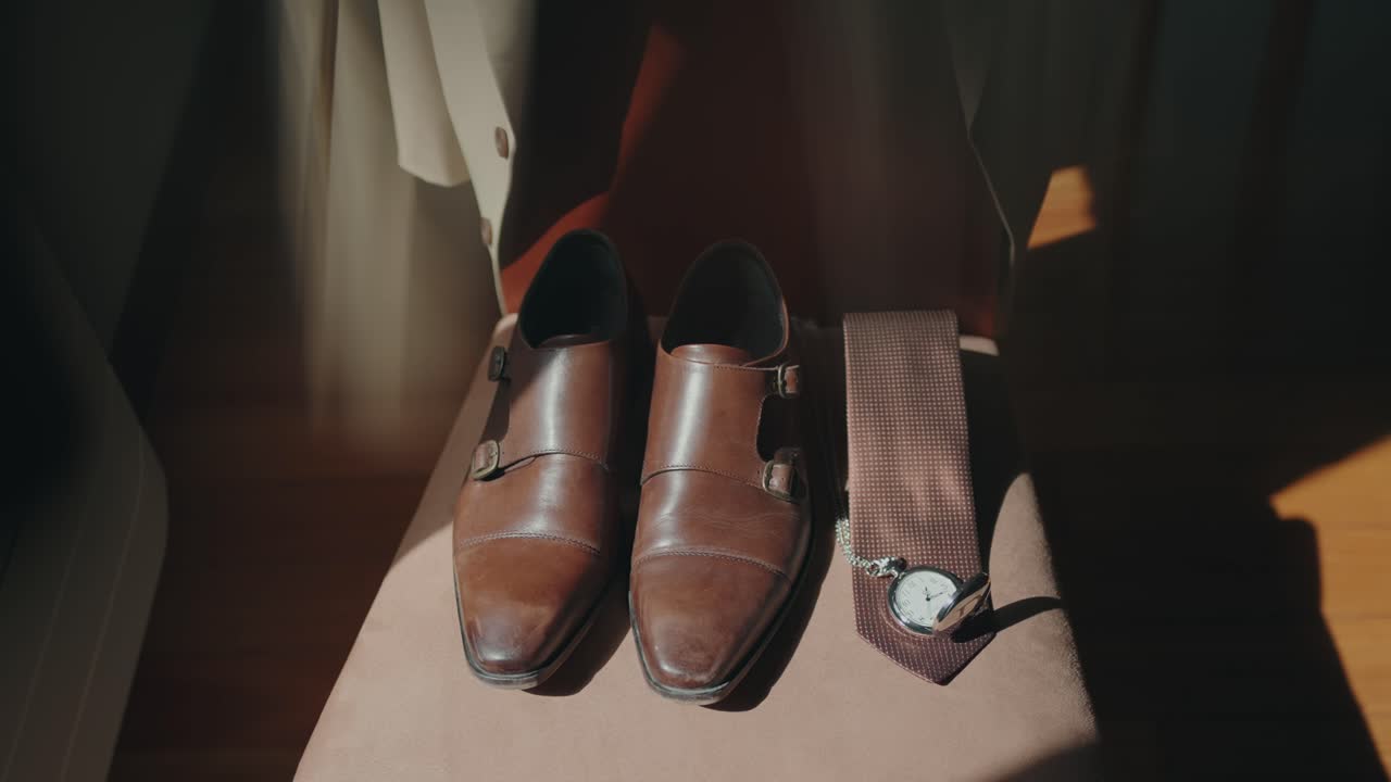Close up of brown shoes tie and pocket watch in wedding preparation scene