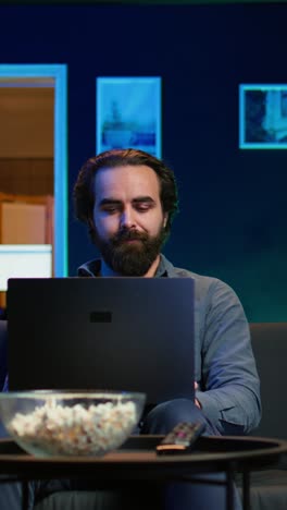 vertical video freelancer working on laptop while watching tv in apartment office