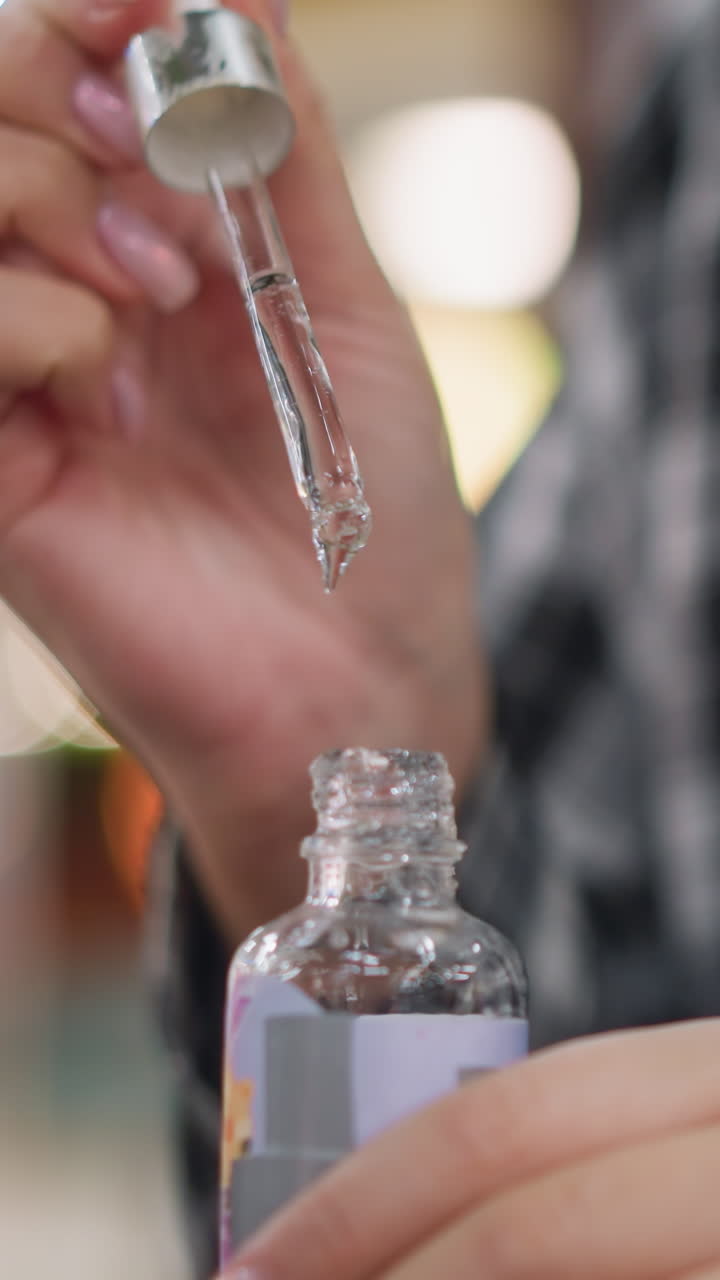 Primer plano de unas manos con una pipeta y una botella de vidrio que demuestran una prueba de formulación clínica de liberación controlada de gotas, solución transparente, mano firme de un técnico, manipulación y medición estériles, laboratorio