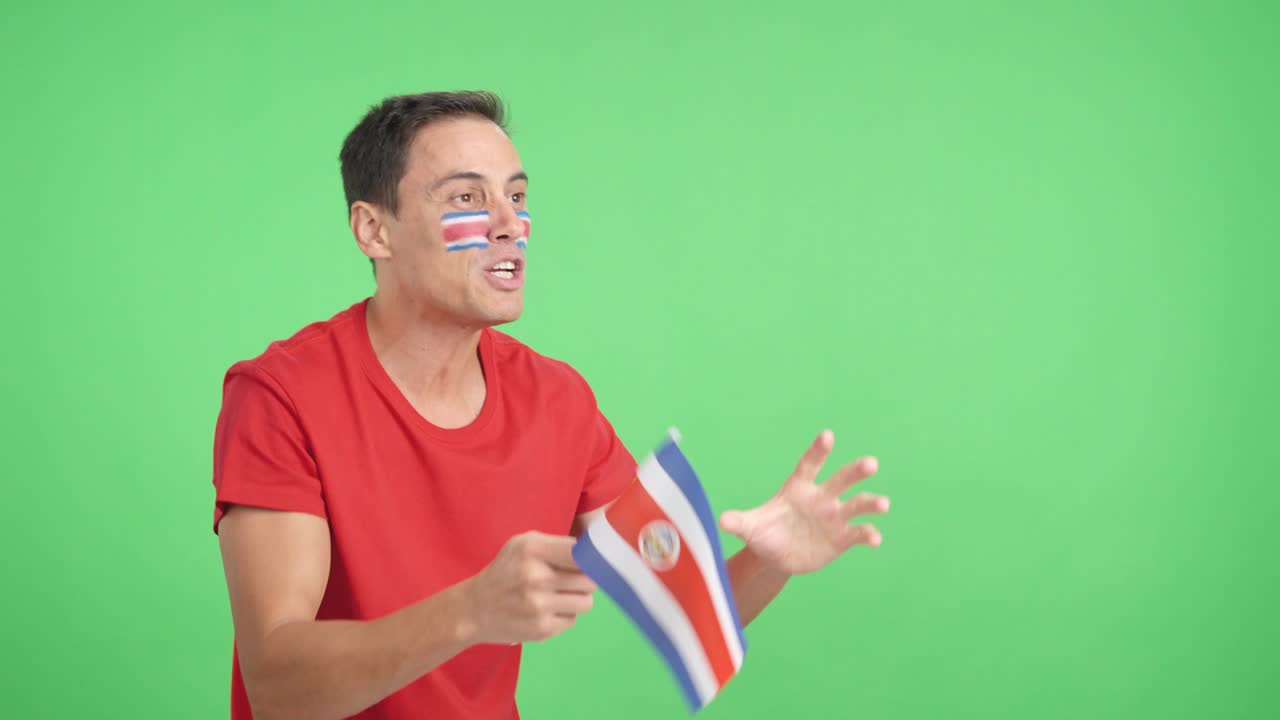Uomo che fa il tifo per la Costa Rica sventolando una bandiera nazionale e guardando altrove