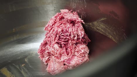 minced meat falling out of industrial machine, close up view