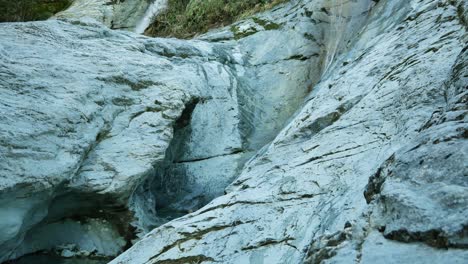 wetsuit man jumps from rocky ledge into limestone slot canyon pool