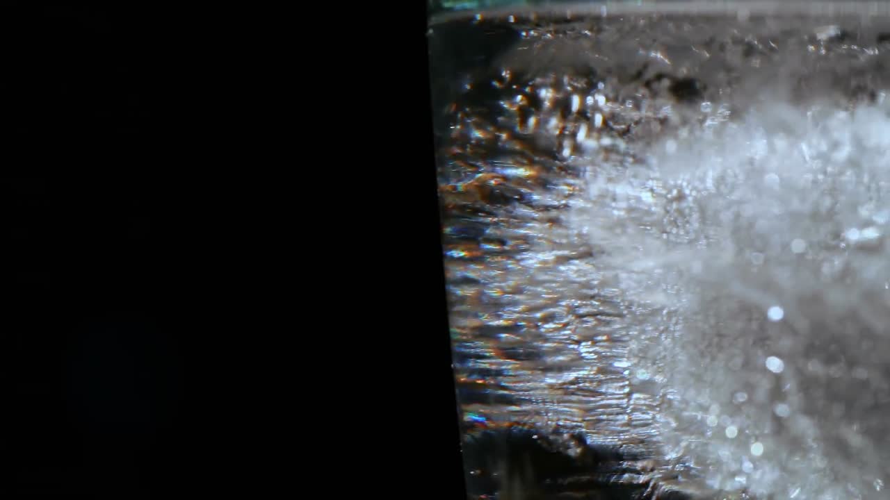 Glass with ice and water against black background 4k