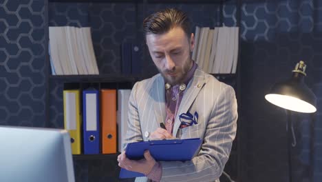 el hombre de negocios elegante y de estilo único trabaja en la oficina, tomando notas, creando planes y horarios.