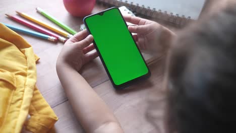 child using a green screen phone at a desk