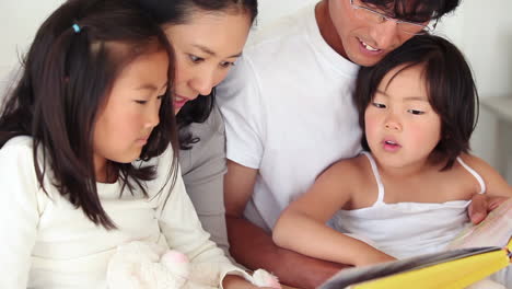 Parents-reading-a-book-to-their-children-as-they-sit-together