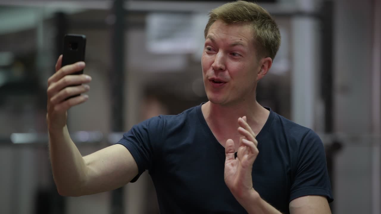 젊은 잘생긴 스칸디나비아 남자 체육관에서 비디오 통화