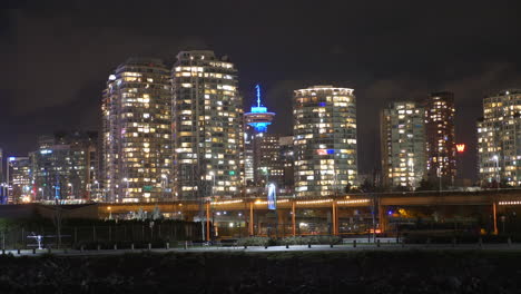 vancouver lookout - harbour centre skyscraper with high-rise building illuminated at night in central business district of downtown vancouver, british columbia, canada